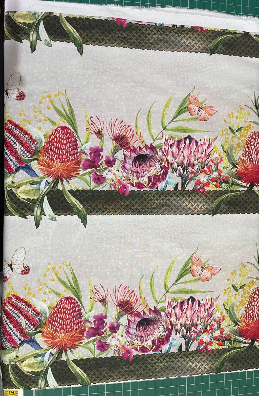 Floral patterned fabric with a green border on a cutting mat.
