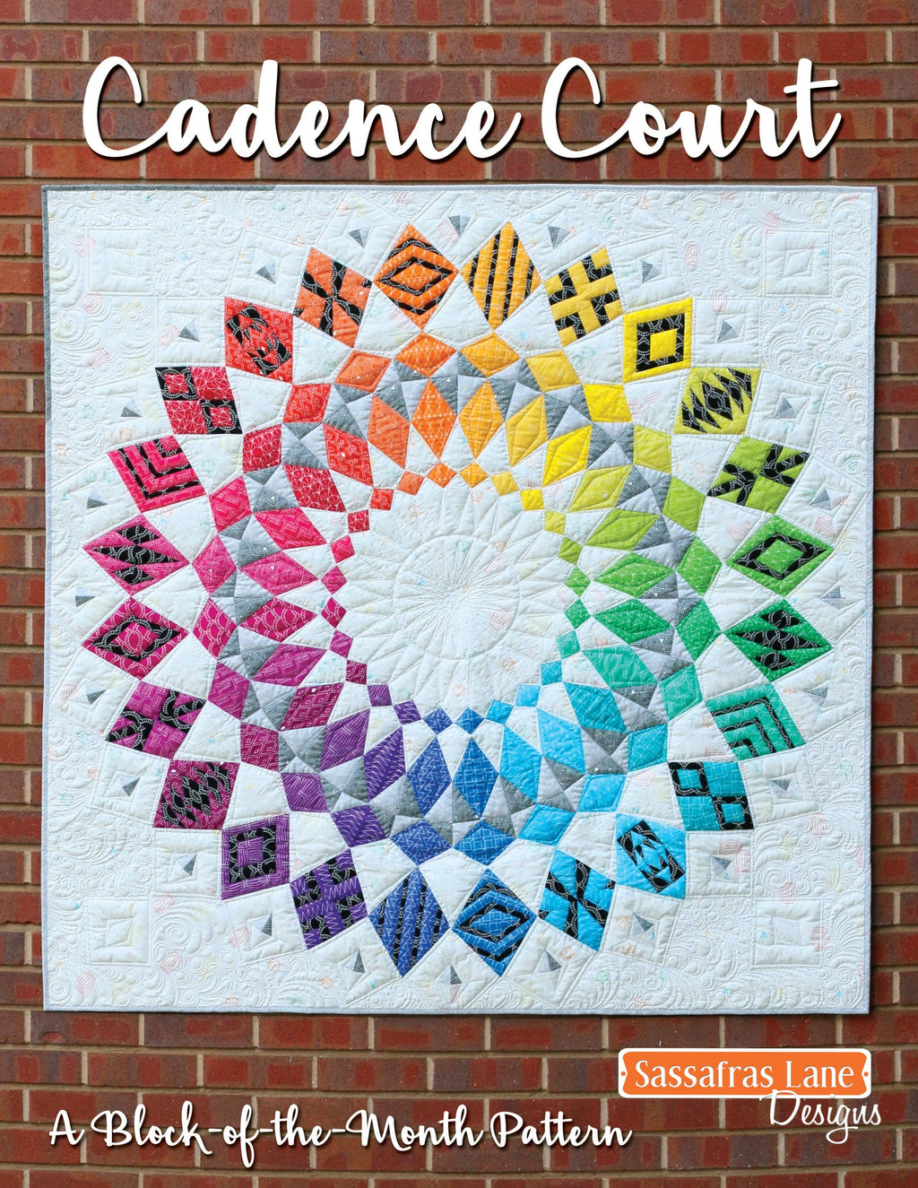 A colorful quilt displayed against a brick wall background, with a title 'Cadence Court' written on it, indicating it is a pattern book for making the quilt.