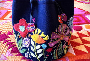 Navy blue bag with colorful floral embroidery on a patchwork quilt background