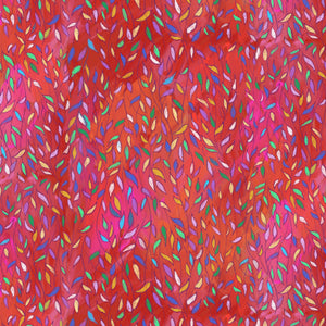 A close-up of a colorful patterned fabric featuring a dense, vertical brushstroke texture in shades of red, orange, and pink, overlaid with small, multicolored leaf-like shapes.