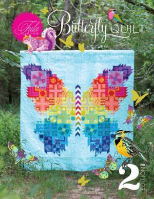 Cover of the Tula Pink Butterfly Quilt 2.0 Pattern featuring a colorful butterfly quilt with various traditional quilt blocks arranged around a central graphic chevron design, accompanied by illustrations of butterflies and a bird in a natural setting.